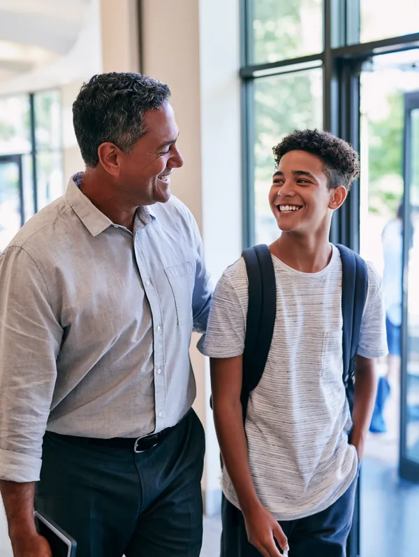 Dad in his 40s walking out of a modern dental clinic with his teenage son, who is flashing a bright new smile after treatment paid with a $1,000 loan