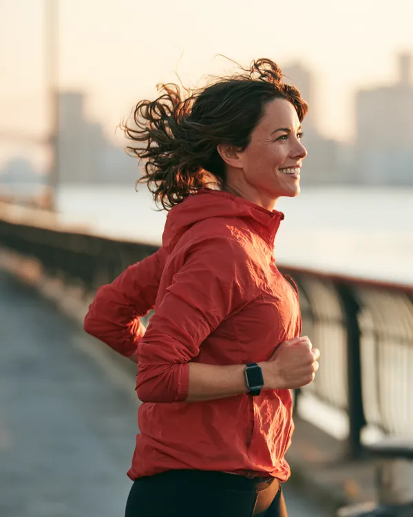 A woman in her 40s jogs along a riverside path at sunrise, looking light and relieved after a loan instant cash consolidation plan