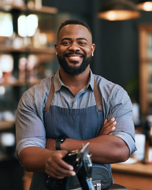 Confident Black barber in his 30s holding clippers in his modern barbershop